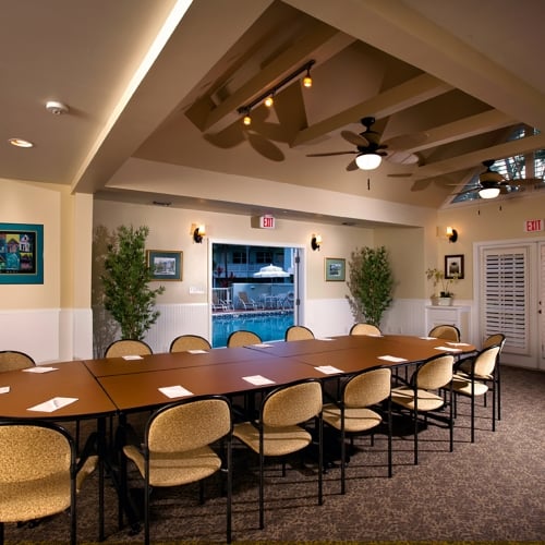 Long wooden conference table lined with chairs and notepads and pens. Room is dimly lit.