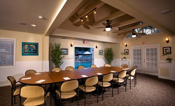 Long wooden conference table lined with chairs and notepads and pens. Room is dimly lit.