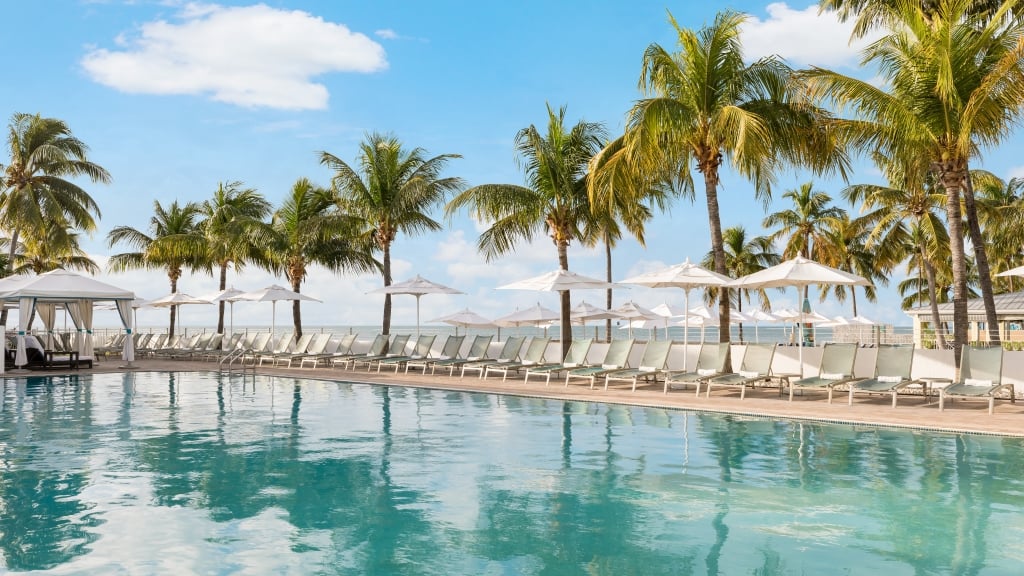 Southernmost Beach Resort Cabana Pool during the day; he pool at the beach club at a Kew West beach: a serene oasis with sparkling blue water and palm trees, perfect for relaxation and fun.