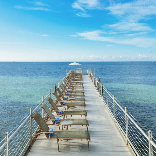 The pier with sun lounge chairs with ocean in background at Southernmost Beach Resort.