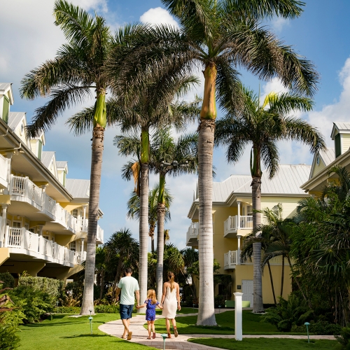 Parents and child walking through the palm tree lined resort.