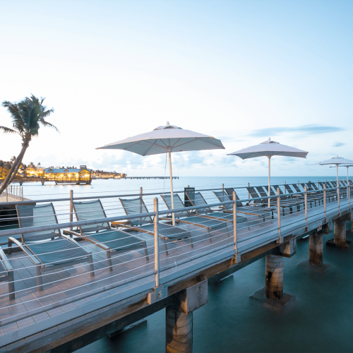 Lounge chairs lined up on the pier at dusk.