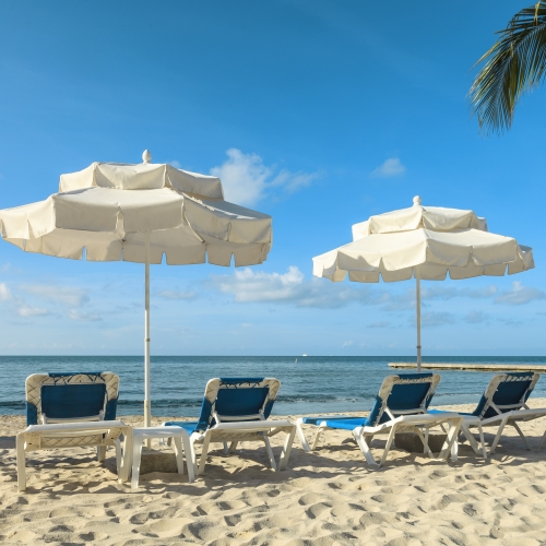 Two umbrellas and lounge chairs on the beach at Southernmost.