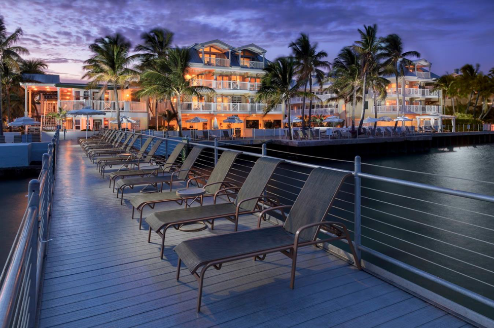 Reclining lounge chairs lined up on a bridge along the water.