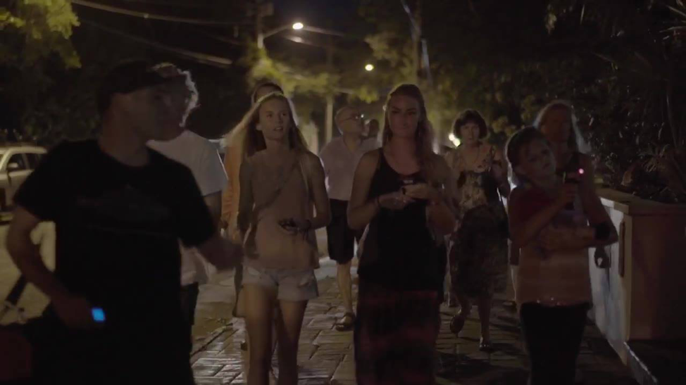 Guide leads group of tourists along dark cobble-stone road during a Haunted Key West Tour.