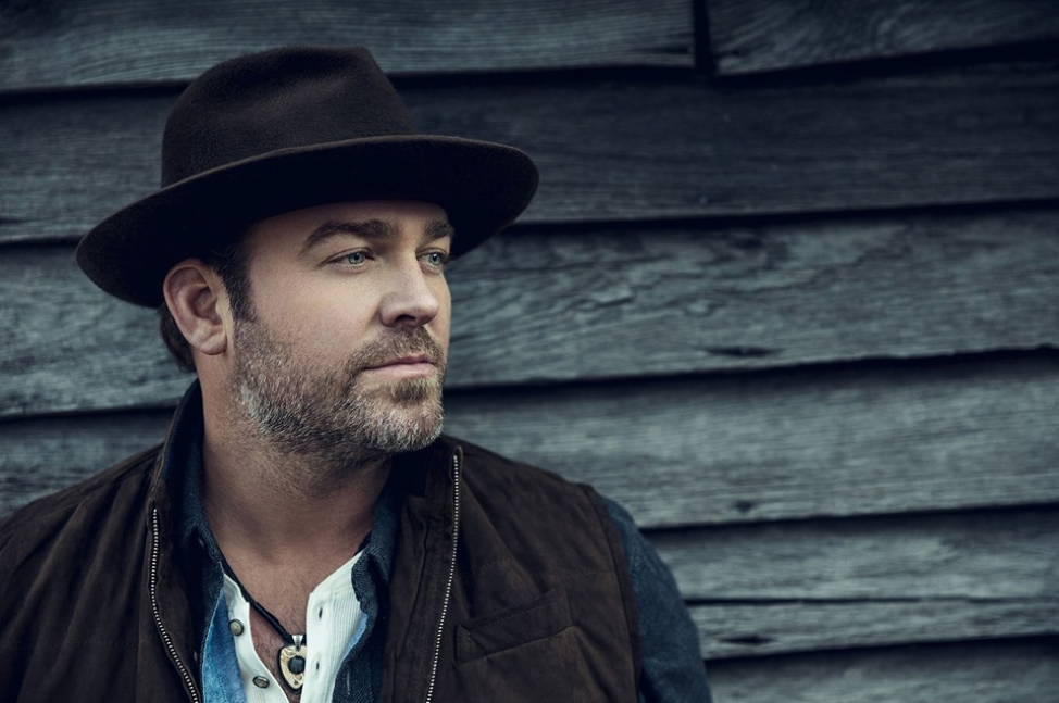 Close up, profile image of musician Lee Brice against wood panelling.