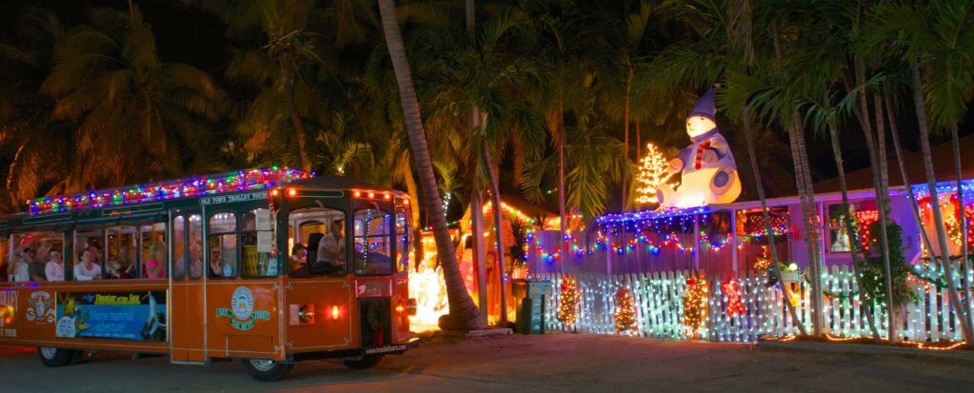 Night-time shot of a train with the Old Town Trolley Tours covered in festive lights.