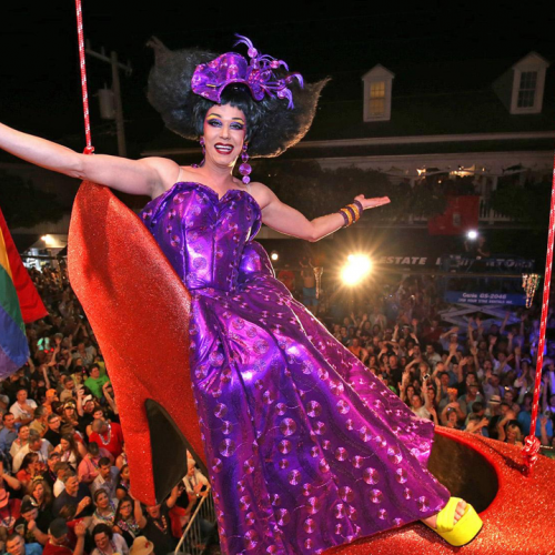 A drag queen sits in an over-sized red high-heeled shoe, suspended in the air, during a New Year's Eve performance on Duval Street.