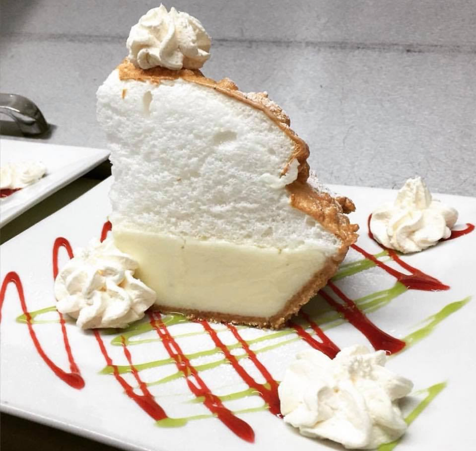 Key lime pie on a plate with a strawberry drizzle