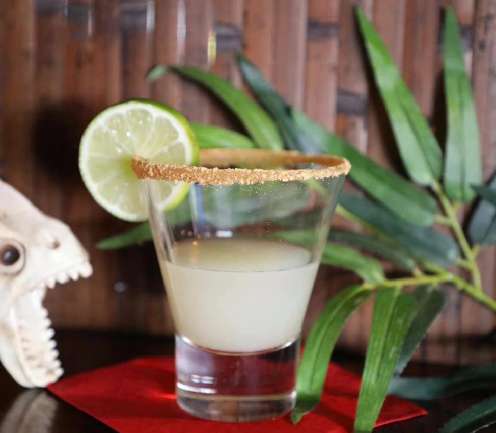 Small shot glass with key lime pie shot and lime wedge on the rim