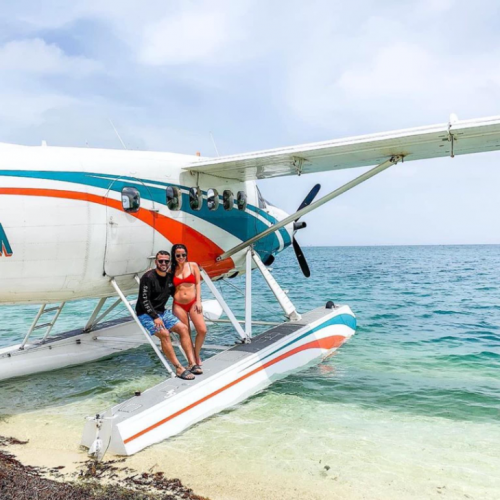 man and woman stand on seaplane pontoon on the beach