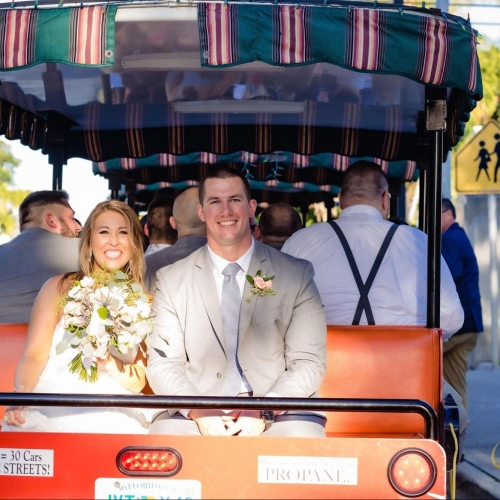 bride and groom smiling are sitting in the back seat of tram