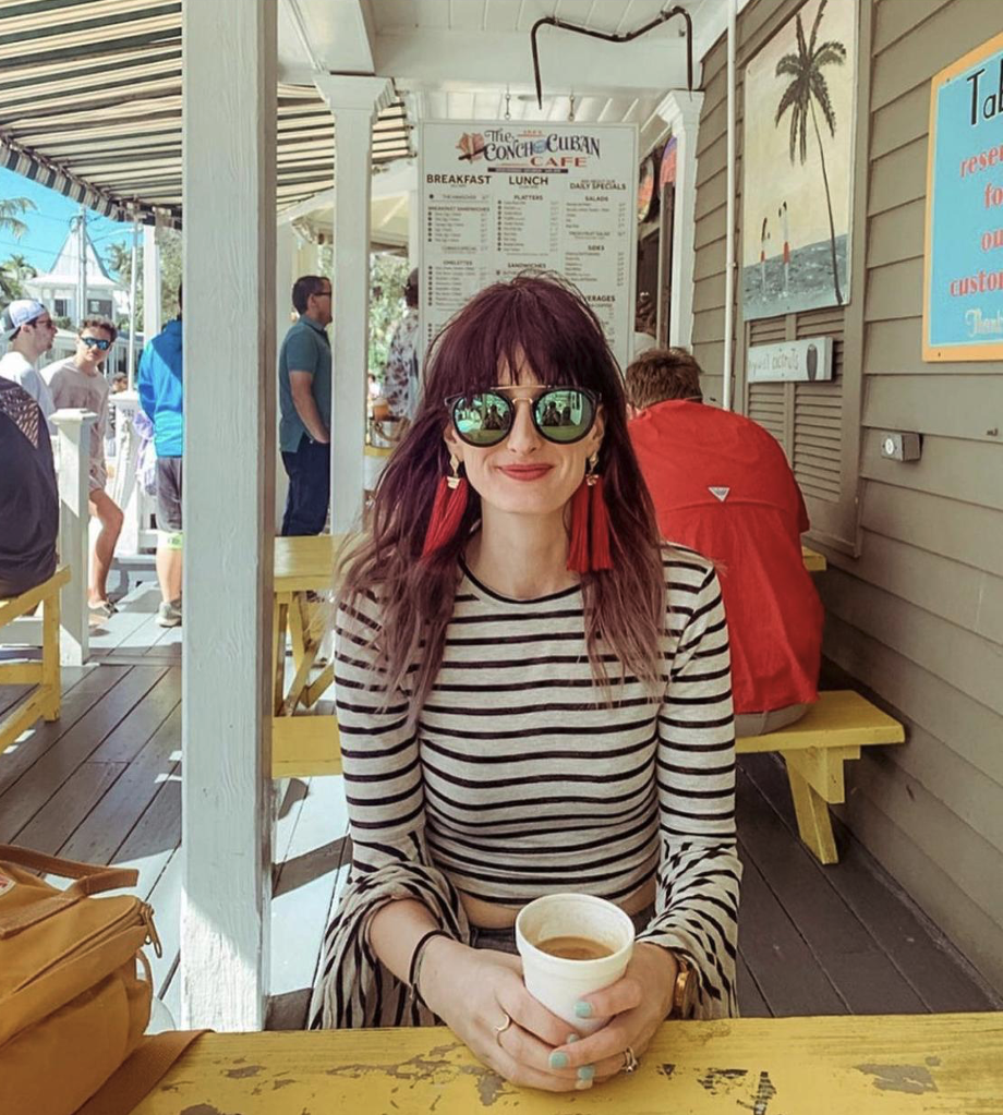 Woman in striped shirt sitting outside on patio holding coffee