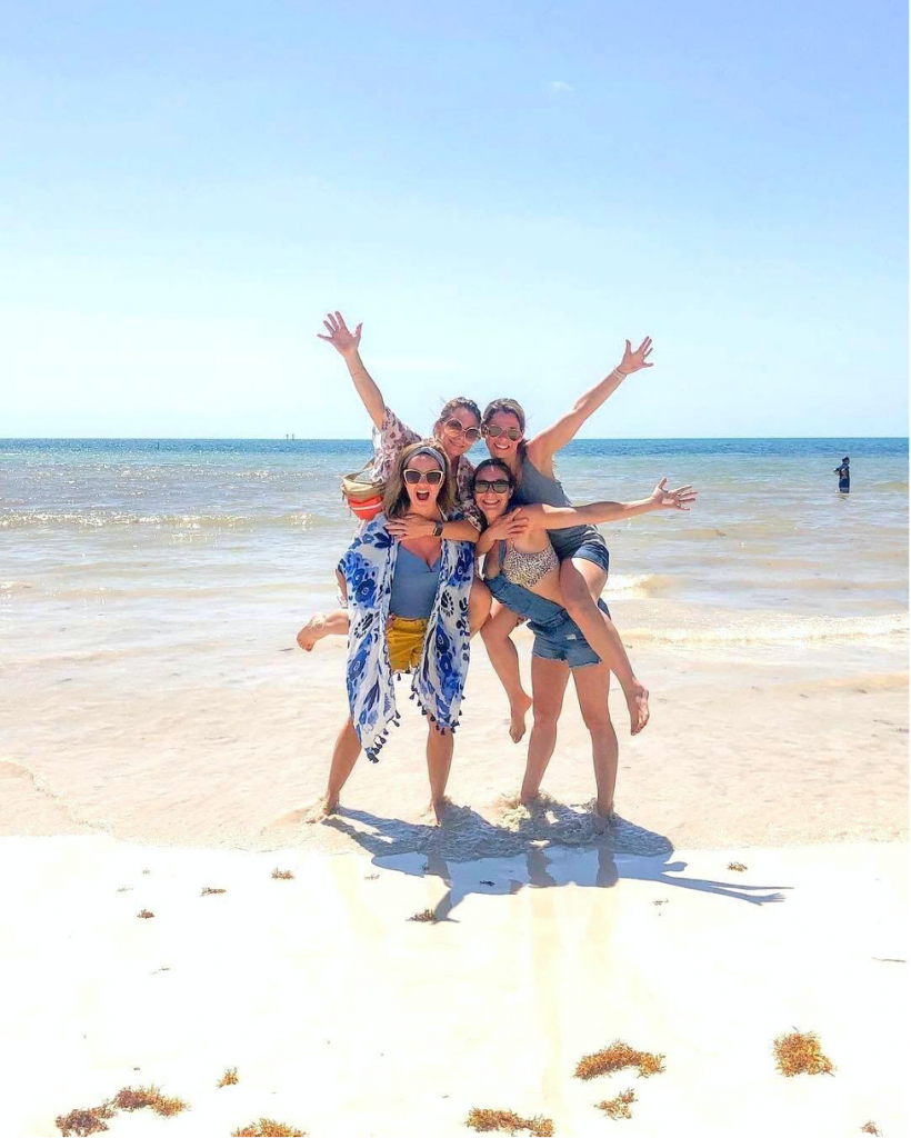 Girls posing for picture on the beach facing the camera.