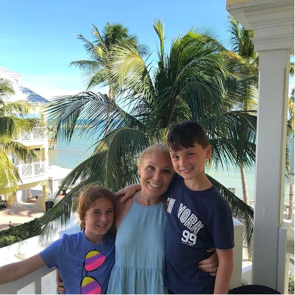 Family hugging on patio with resort backdrop.