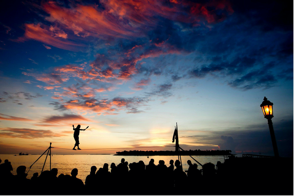 Key West Sunset by the water with man walking on tight rope.