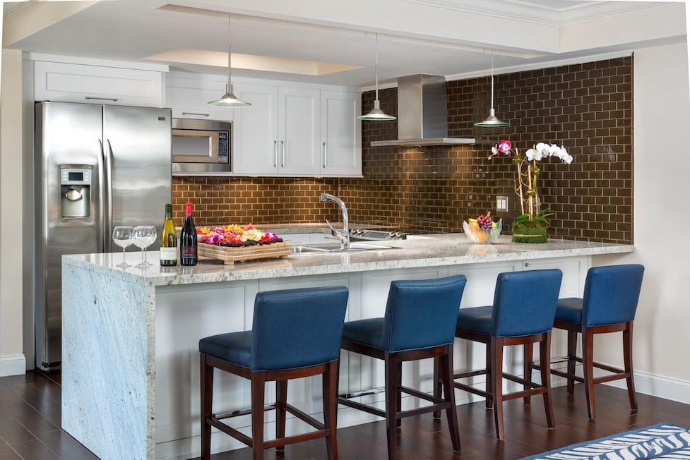 A modern and bright kitchen with an island and four navy blue bar stools