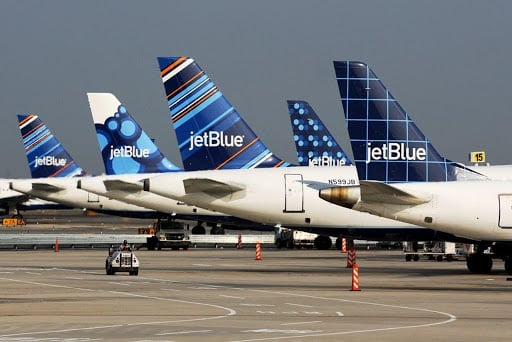 Five JetBlue airplanes lined up on the pavement