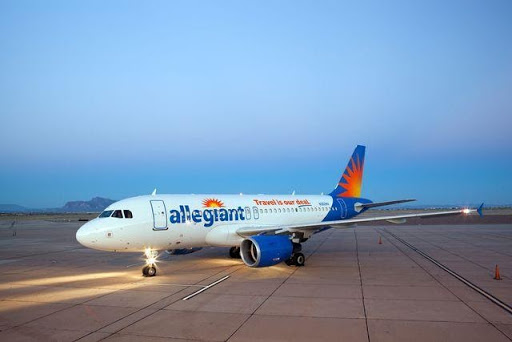 An Allegiant Airline airplane on the pavement at dusk getting ready for take off