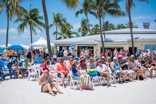 A packed beach full of people in beach chairs ready for a show