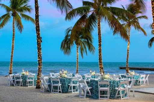 Dining set up at dusk on the beach surrounded by palm trees