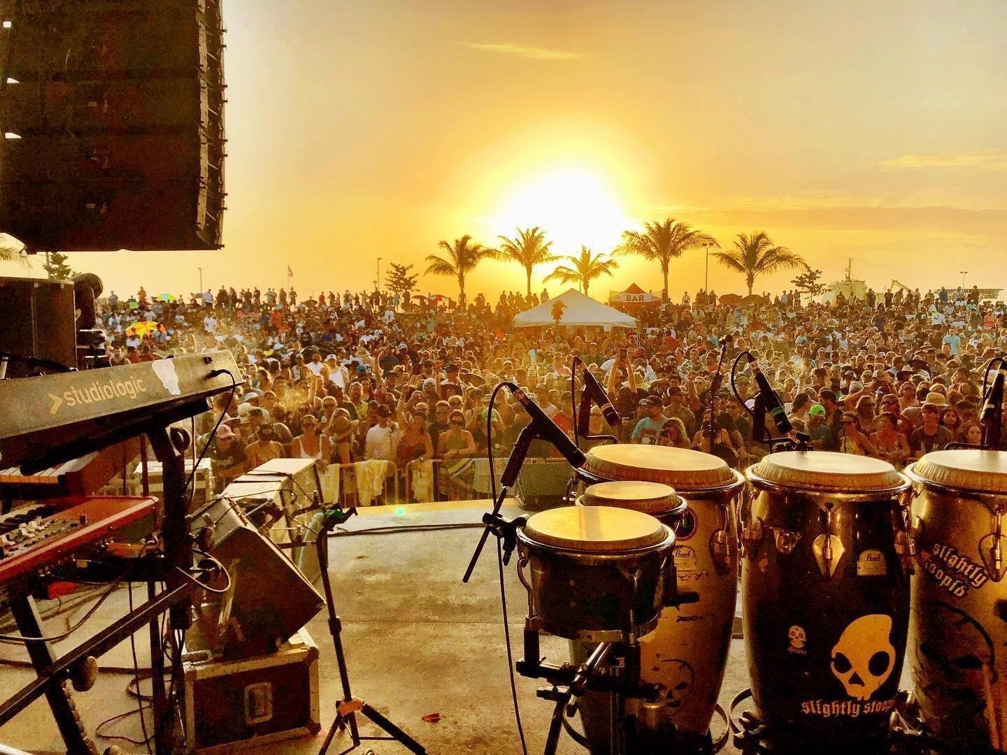 View of an outdoor concert packed with people at sunset