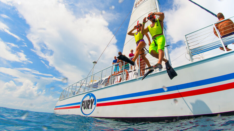 A man and a women jumping off a boat to go snorkeling