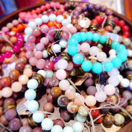 Colorful beaded bracelets rest intertwined in a pile, showcasing various vibrant hues, including turquoise and pink, on a wooden surface, typical of artisan markets in Key West.