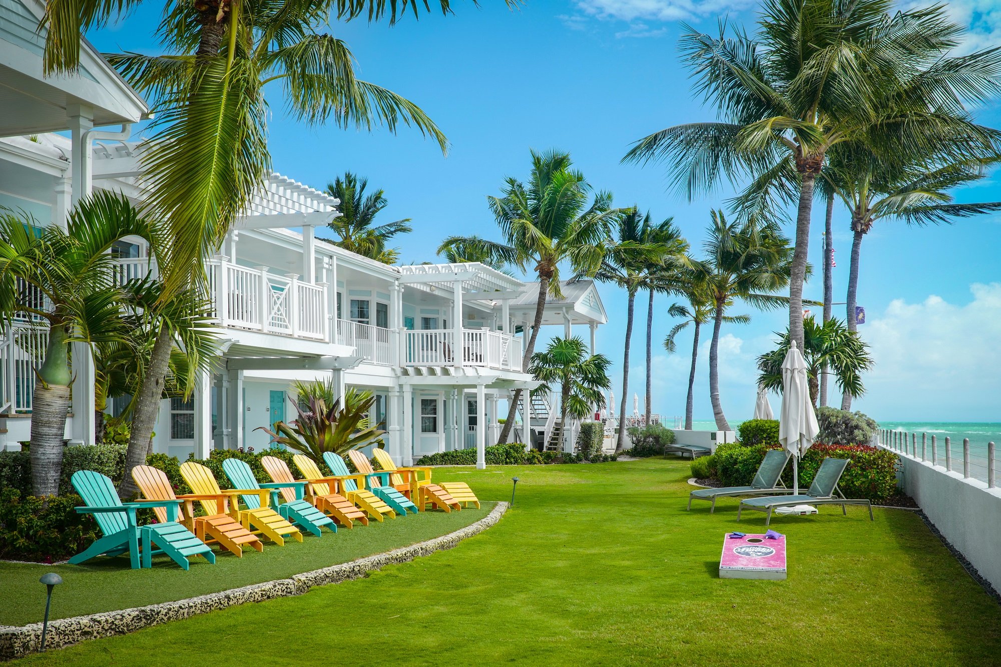 Southernmost resort facing the ocean; Key West resort lounging chairs facing the ocean by palm trees and a grass field.