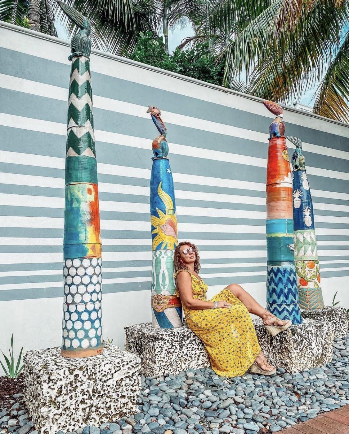 Woman sitting beside colourful pillars