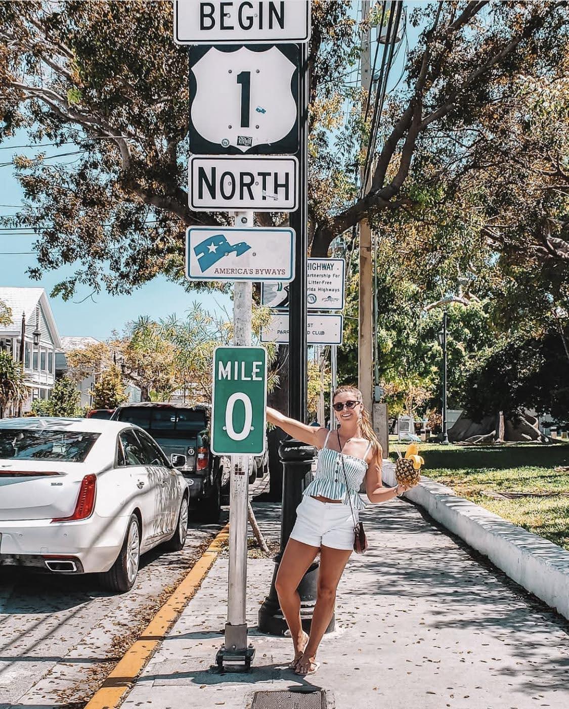 Woman posing beside a zero mile sign