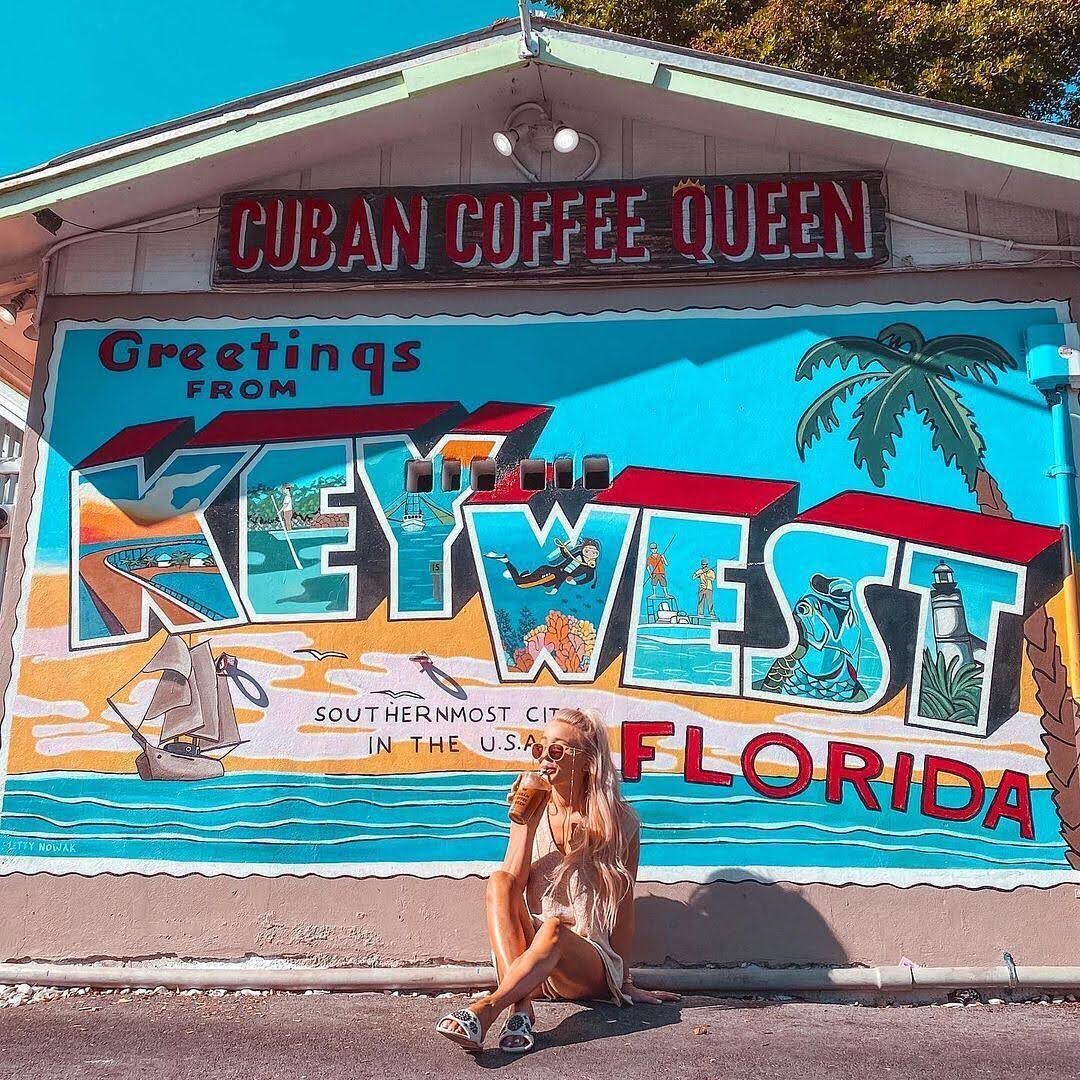 Woman sitting in front of a post card mural