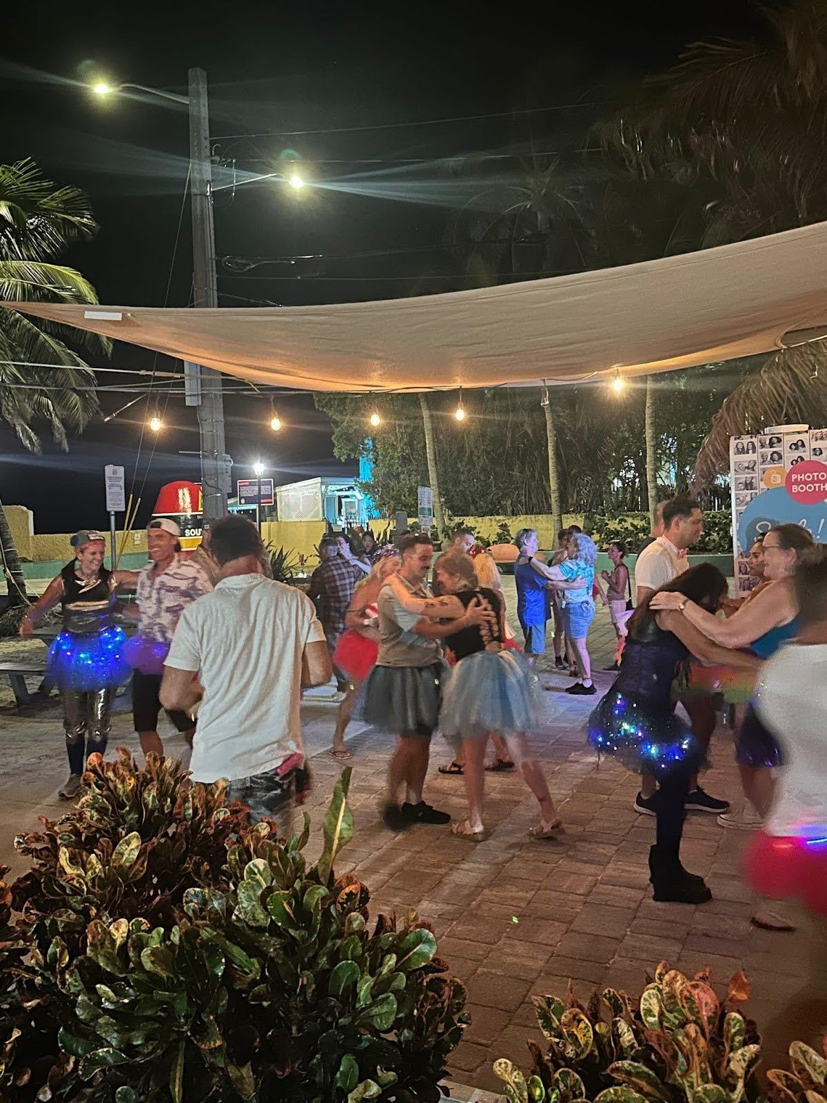Couples dance under lights.