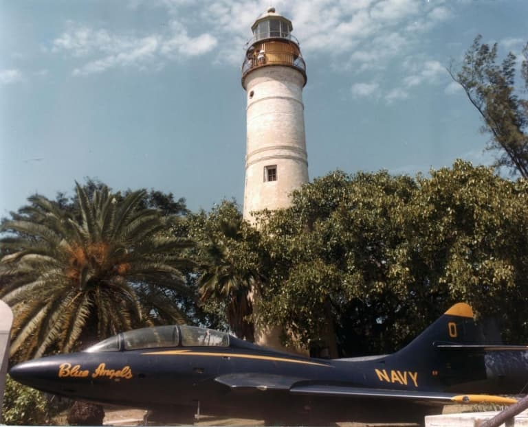 blue angel jet next to a lighthouse
