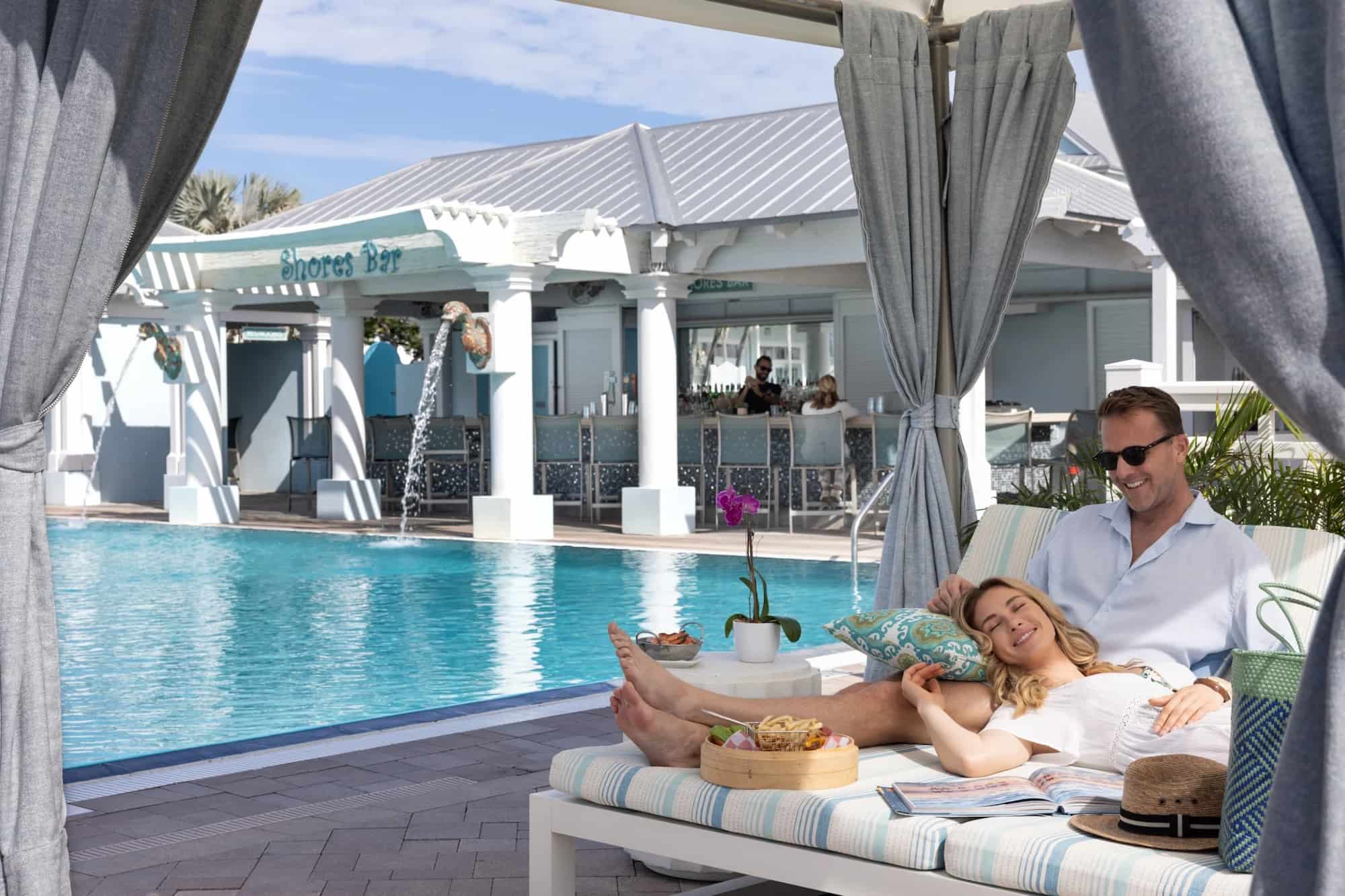 man and woman lounging by the pool