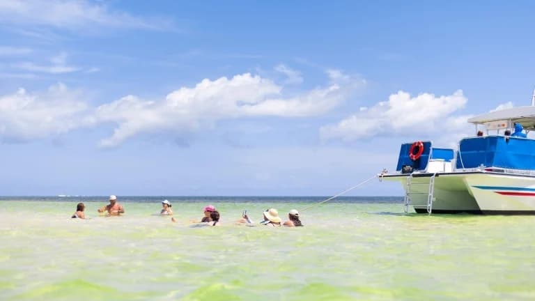 people swimming next to sailboat