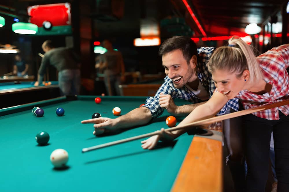 couple play pool at bar