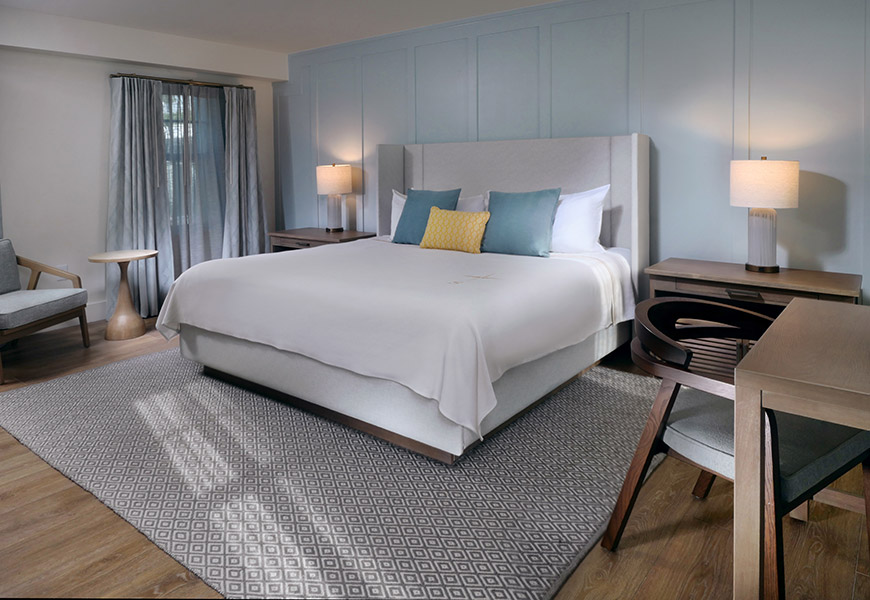 A hotel room with a king-sized bed, desk, and window