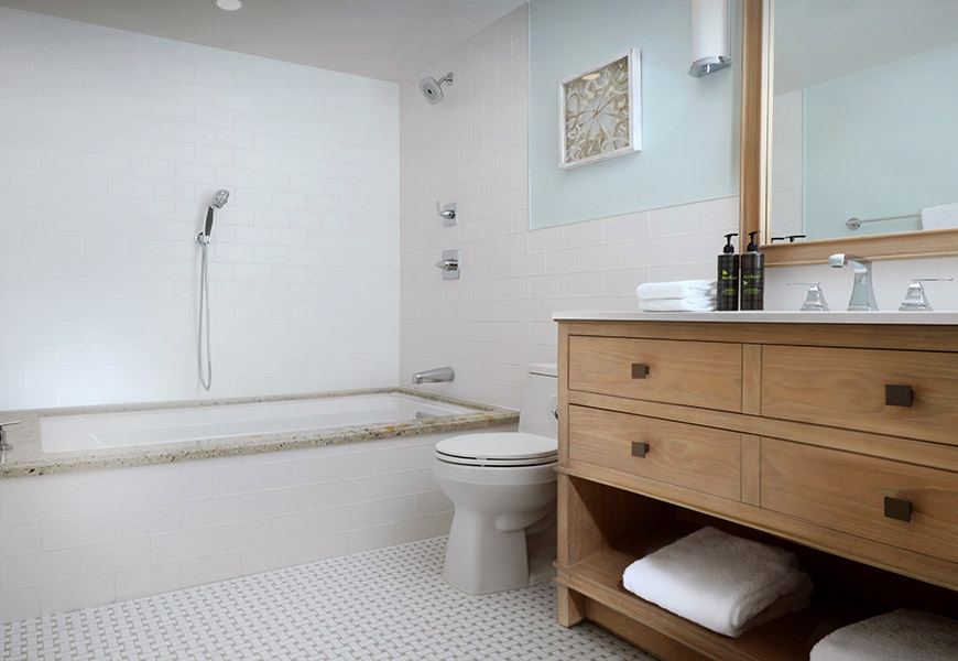 A clean bathroom with a bathtub, toilet, and wooden vanity.