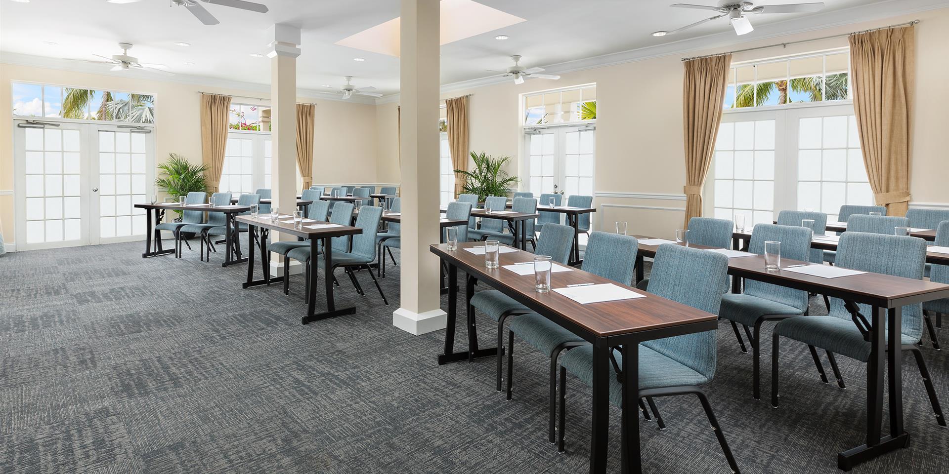 A well-lit meeting room with tables, chairs, and windows