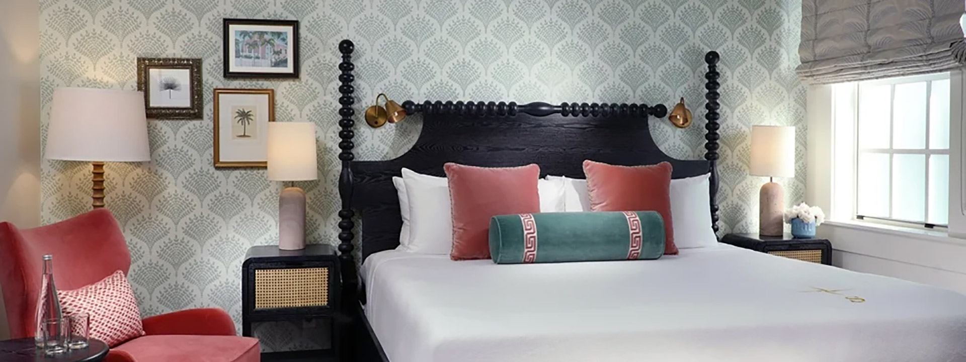 A neatly made bed with white bedding and pillows in a room with a four-poster bed, a red chair, and a window.