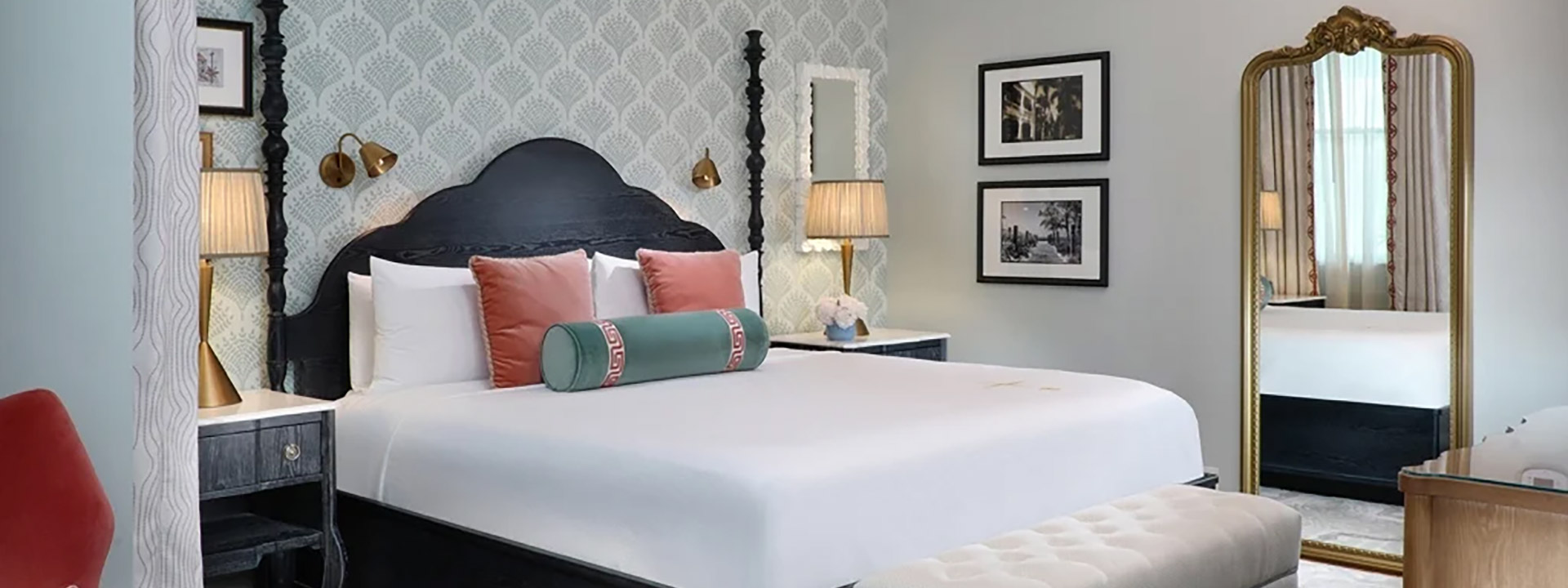 A wide view of a guest room with a large bed, nightstands, and a mirror